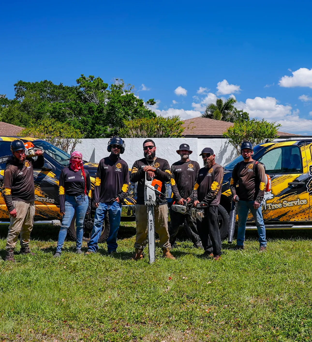 A group of men are standing in a field holding chainsaws.